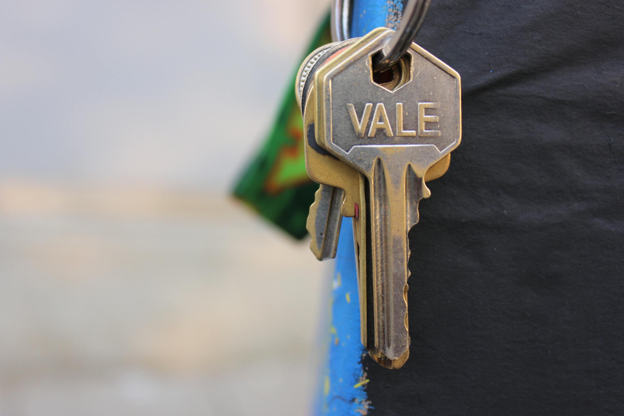 A detailed view of a metallic key with 'Vale' engraved on it, hanging against a blurred background.